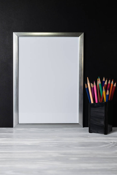 Simular marco blanco y lápices de colores en estante de madera y pizarra
 - Foto, Imagen