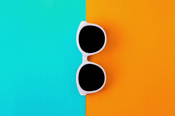 Солнечные стильные белые солнцезащитные очки на ярко-голубом и желто-оранжевом фоне, вид сверху, изолирован. Принято. Плоский лежал
 - Фото, изображение