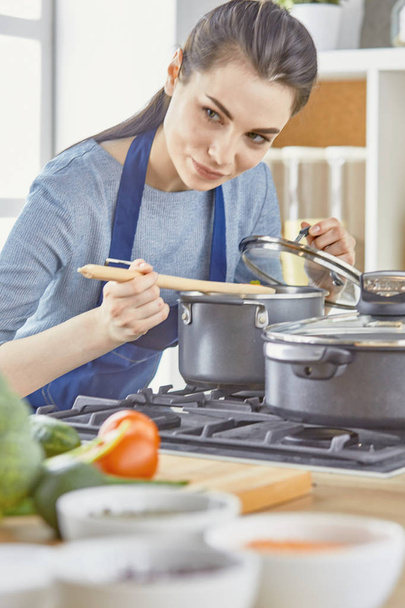 Menina bonita está degustando comida e sorrindo enquanto cozinha em kit
 - Foto, Imagem