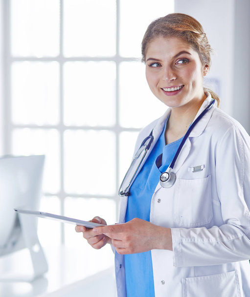 Young woman doctor is standing with board with clipboard smilin - Foto, immagini