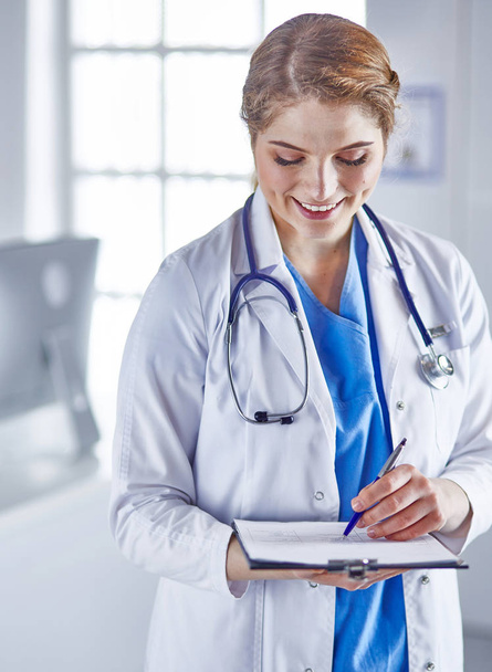 Jovem médico está de pé com placa com prancheta de sorriso
 - Foto, Imagem