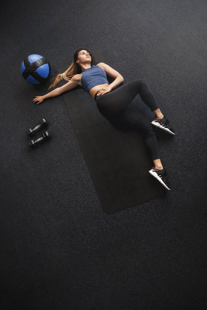 Attractive woman doing bicycle crunches, fitness side-abs workout lead active and healthy lifestyle, lying rubber mat gym near medicine ball, dumbbells, wear sportswear, workout abs exercises - 写真・画像