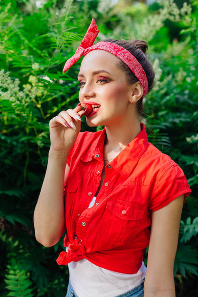 Beautiful young pin up girl with bright make up eating fresh natural strawberry. - Fotoğraf, Görsel