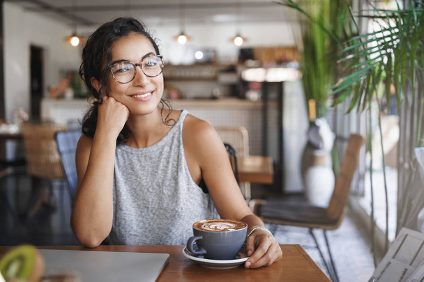 Relaxed attractive woman lean arm tilt head cute smiling camera sit cafe near window closed laptop finished work enjoy nice friendly conversation drink cappuccino waiting boyfriend near office - Foto, afbeelding