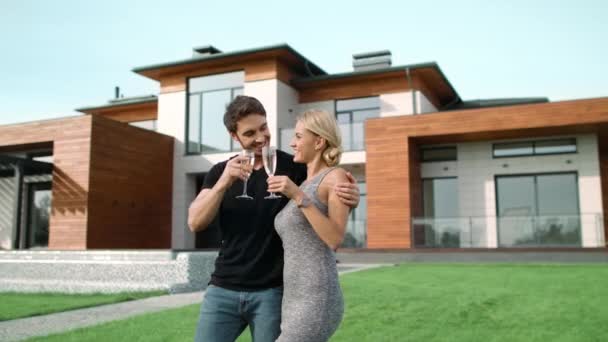 Um casal rico a beber champanhe perto de casa. Sorrindo pessoas abraçando fora villa
. - Filmagem, Vídeo