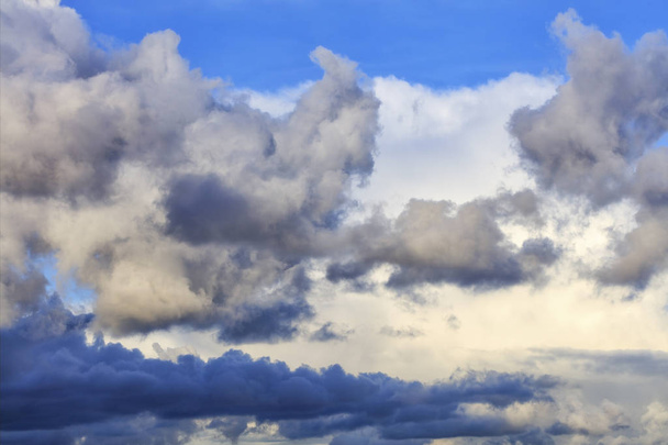 Nuvens de tempestade se reúnem em uma pilha fechando um céu azul
 - Foto, Imagem