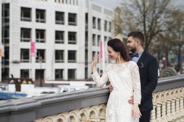 Wedding photo shooting. Bride and bridegroom walking in Amsterdam. Stand on bridge and hug. - Photo, Image
