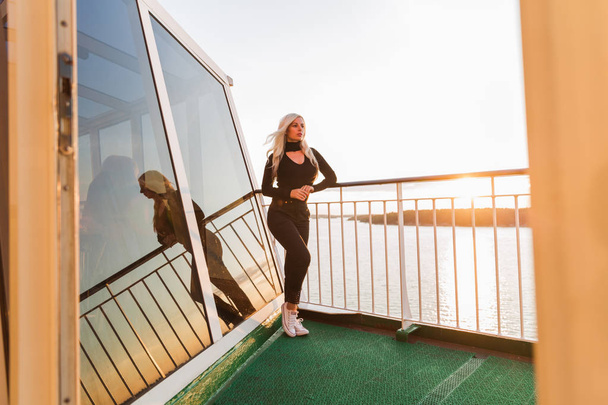 The stylish young woman standing on the ship by the sea outdoors - Foto, afbeelding