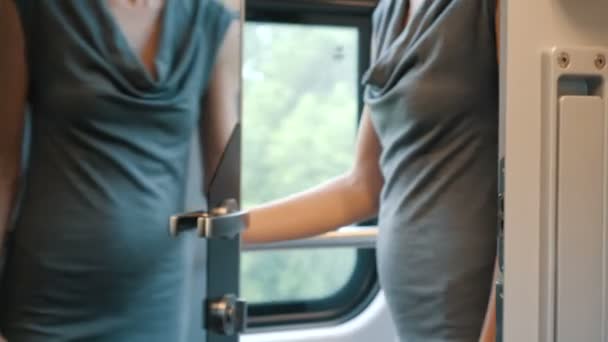 Egy fiatal nő kinyitja, és megnyit egy tükör ajtó fém fogantyúval és belép a modern kényelmes vasúti rekesz. A vonat utas feloldja az ajtót, és vesz egy helyet az ablak mellett. - Felvétel, videó