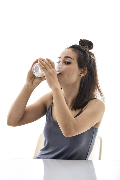 jonge vrouw drinken melk op tafel - Foto, afbeelding