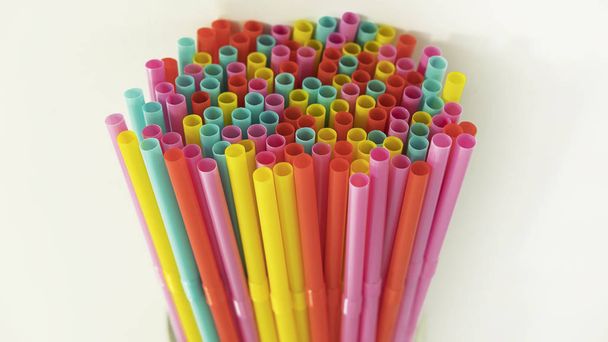 Multi colored plastic drinking straws held together against a neutral background. Single-use disposable flexible straws, causing oceans pollution, harming marine, difficult to biodegrade or dissolve. - Photo, Image