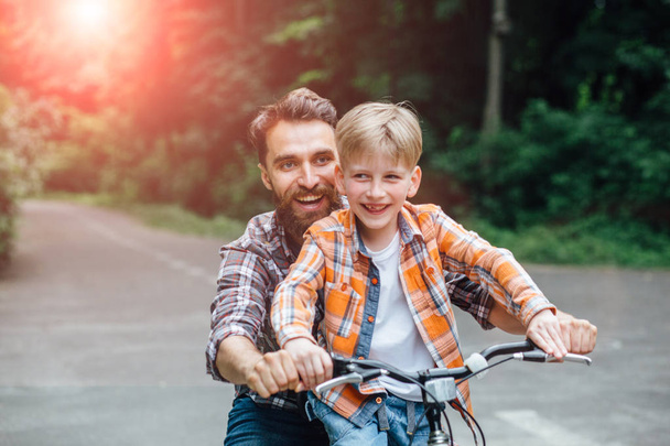 Happy laughing father with his son on a balance bike. - Zdjęcie, obraz
