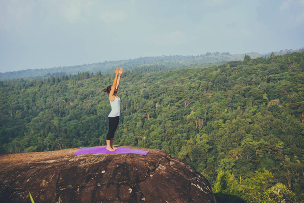 Aziatische vrouwen ontspannen in de vakantie. Spelen als yoga. Op de berg rots klif. Natuur van bergbossen in Thailand - Foto, afbeelding