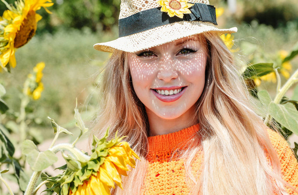 ヒマワリと草原でポーズオレンジのスウェットシャツを着た美しい白人女性. - 写真・画像
