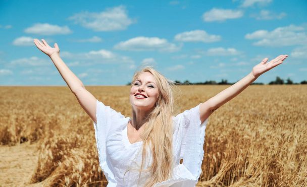 Hermosa mujer caucásica en vestido blanco posando en el prado con trigo
. - Foto, imagen
