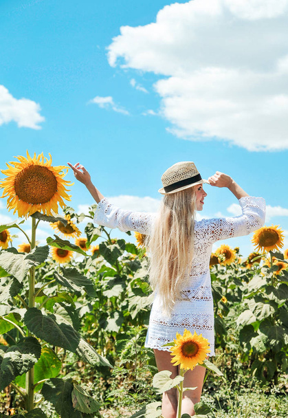 Красива біла жінка в білій сукні позує на лузі з соняшниками
. - Фото, зображення