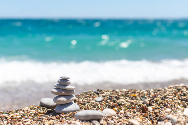 Pirâmide de pedras. Obo de seixos. Torre de pedra na praia contra o mar azul. Equilíbrio, paz de espírito, pedras formam uma pirâmide na praia de seixos
. - Foto, Imagem