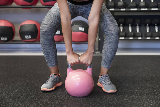 Close-up shot of a woman's toned arms and hands lifting a very heavy kettlebell and performing ballistic exercises by combining cardio, lifting, and flexibility training as part of her fitness routine - Zdjęcie, obraz