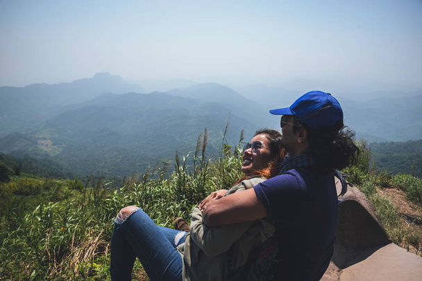Rakastaja pari naista ja miestä aasialaiset matkustavat rentoutua lomalla. Istukaa ja katsokaa maisemaa vuorella. Mountain Parkissa onnellisena. patikointi vuorilla. Thaimaassa
 - Valokuva, kuva