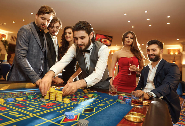 A young man with friends makes bets on roulette in a casino. - Foto, imagen