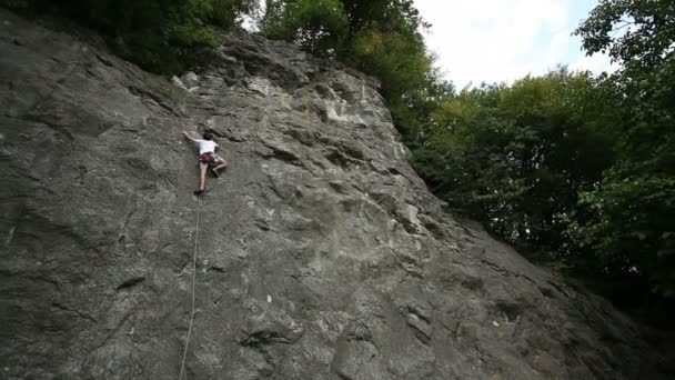 Man rock climbing in beautiful nature shot from below - Materiał filmowy, wideo