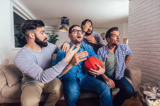 Ευτυχισμένοι φίλοι ή παίκτες του μπάσκετ βλέποντας παιχνίδι μπάσκετ στην τηλεόραση  - Φωτογραφία, εικόνα
