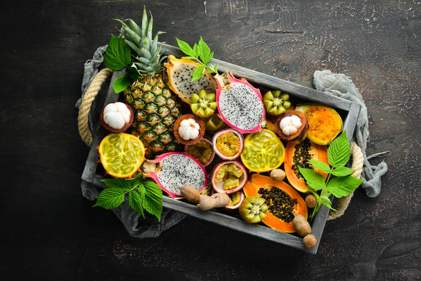Tropical fruits on a brown background: papaya, mangosteen, cactus fruit, pytahaya, pineapple. Top view. Free space for text. - Photo, Image