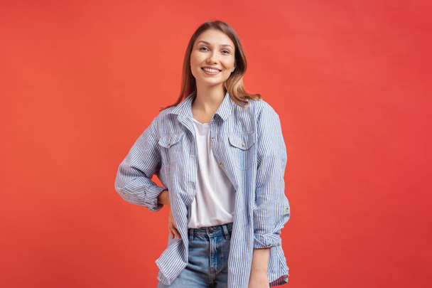 Pretty female model posing with a smiling face expression on red background - Photo, Image