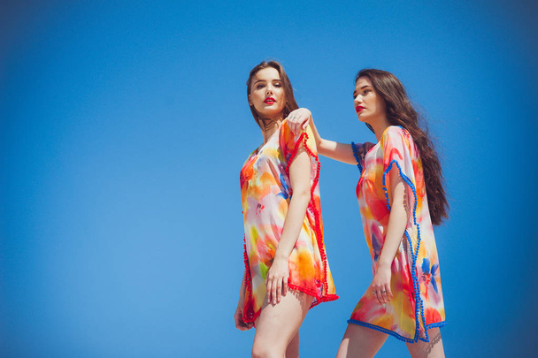 Deux jeunes femmes magnifiques portant des maillots de bain, fond bleu ciel - Photo, image