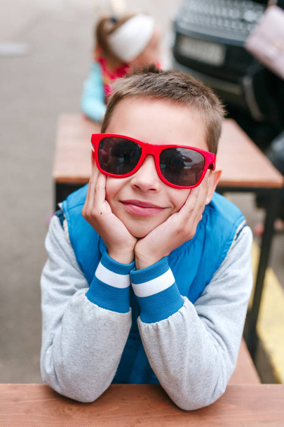 Portrait happy smiling boy in red sunglasses in city - Foto, Imagem