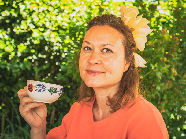 Retrato de una mujer bonita en el jardín con una taza de té. Suma
 - Foto, imagen