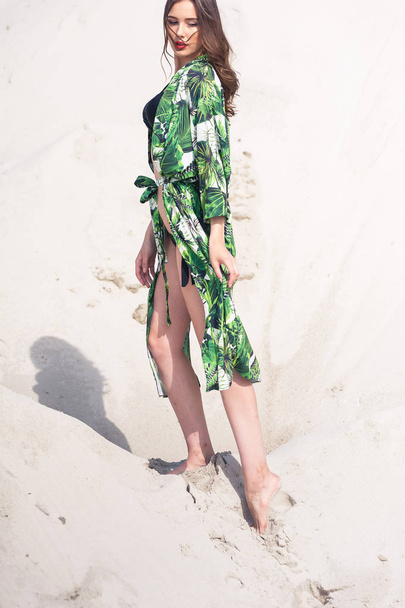 Kaunis nuori nainen jäähdytys rannalla vihreissä uimapuvuissa
 - Valokuva, kuva