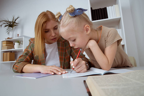 Doing tasks and studying concept. Sitter with girl writing homework. - Photo, Image