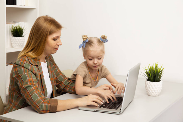 Mother with daughter learning something by using computer indoor. - 写真・画像