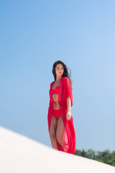 Красива жінка позує на піску. Літній модний червоний купальник
. - Фото, зображення