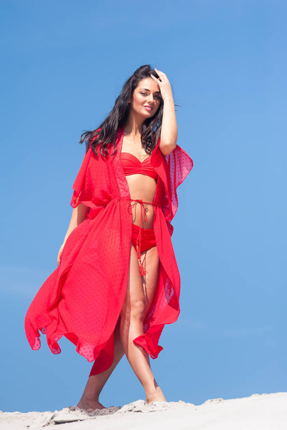 Beautiful woman posing on the sand. Summer fashion red swimwear. - Photo, Image