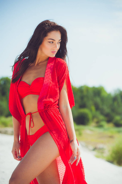 Beautiful woman posing on the sand. Summer fashion red swimwear. - Photo, Image