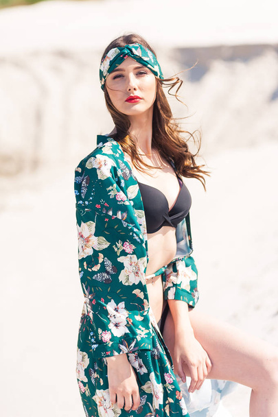 Kumsalda yürüyen güzel genç bir kadın, yeşil çöl kıyafetleri. - Fotoğraf, Görsel