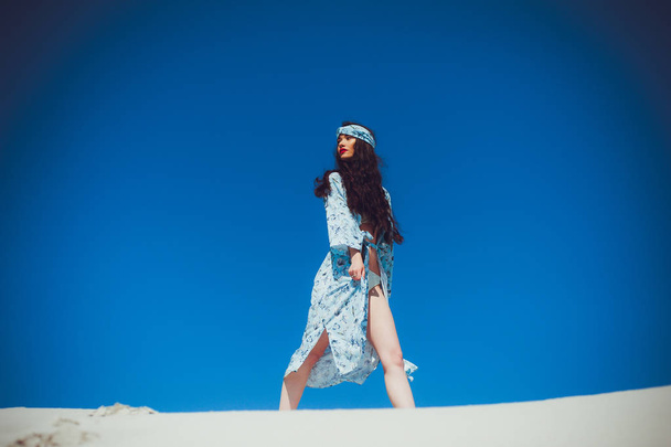 Girl walks on desert. Beautiful woman is walking, staing on sand or dune. Fashion swimwear - Photo, Image