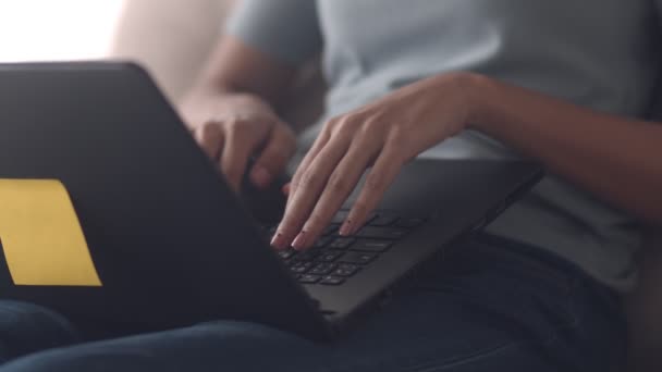 Slow Motion: Cierra las manos escribiendo con computadora portátil compartiendo bloguero en línea influencer, mujer asiática navegando por las redes sociales mientras está sentada en el sofá en la sala de estar en casa
. - Metraje, vídeo