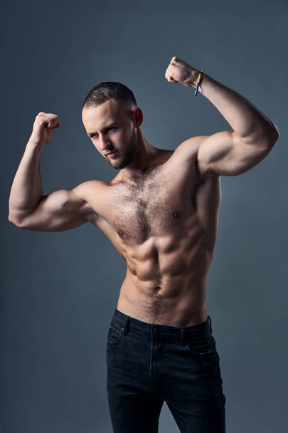 Muscular shirtless man showing his biceps - Foto, afbeelding