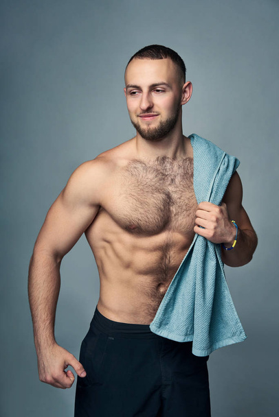 Muscular shirtless man with towel over shoulder - 写真・画像