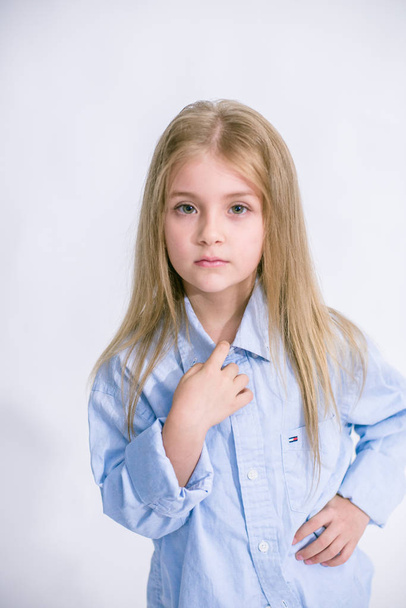 Beautiful fashionable little girl with blond hair in jeans clothes on a white background in studio - 写真・画像