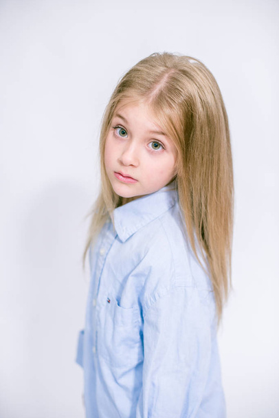 Beautiful fashionable little girl with blond hair in jeans clothes on a white background in studio - Foto, Imagen
