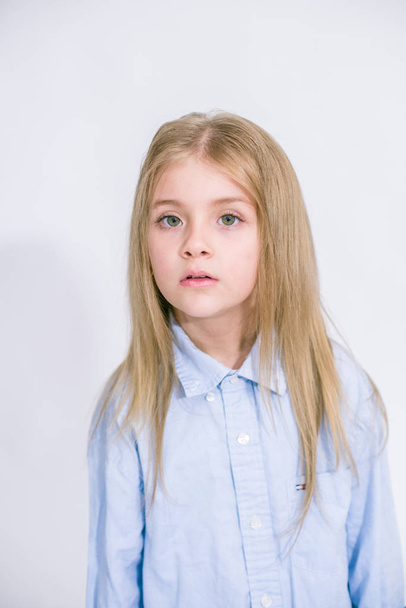 Beautiful fashionable little girl with blond hair in jeans clothes on a white background in studio - 写真・画像
