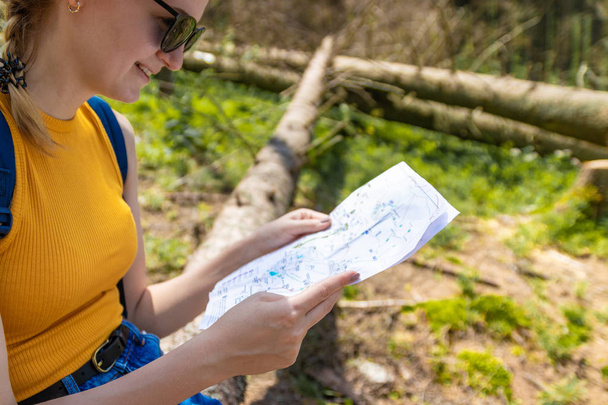 Young girl hiker pointing hands on trekking plan - Photo, Image