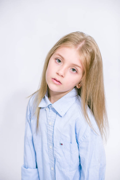 Beautiful fashionable little girl with blond hair in jeans clothes on a white background in studio - Valokuva, kuva