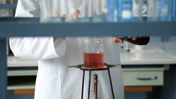 Prise de vue du jeune étudiant mélangeant du liquide sur le feu dans le cadre d'une expérience
 - Séquence, vidéo