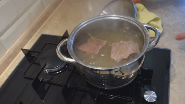 man comes to a gas stove, and closes with a towel cover the pan  - Záběry, video