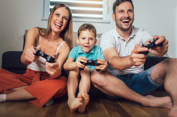 Famille heureuse jouant à des jeux vidéo à la maison et s'amusant ensemble - Photo, image